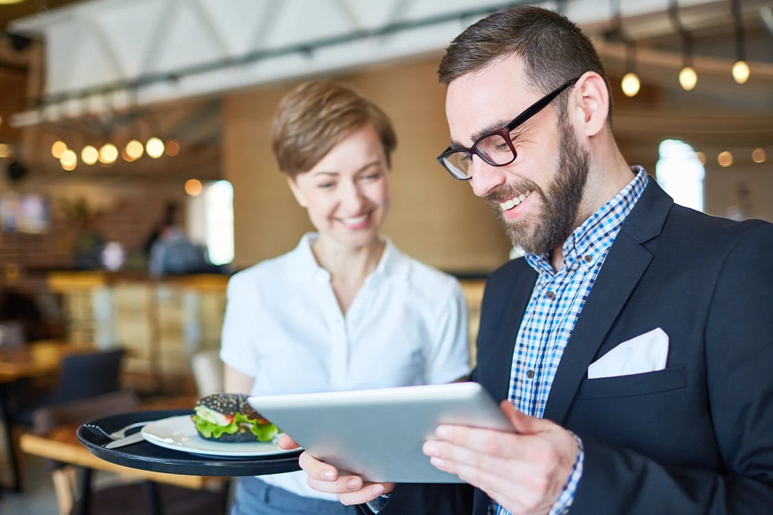 Ein Mann und eine Frau stehen in einem Betriebsrestaurant und unterhalten sich über die Digitalisierung