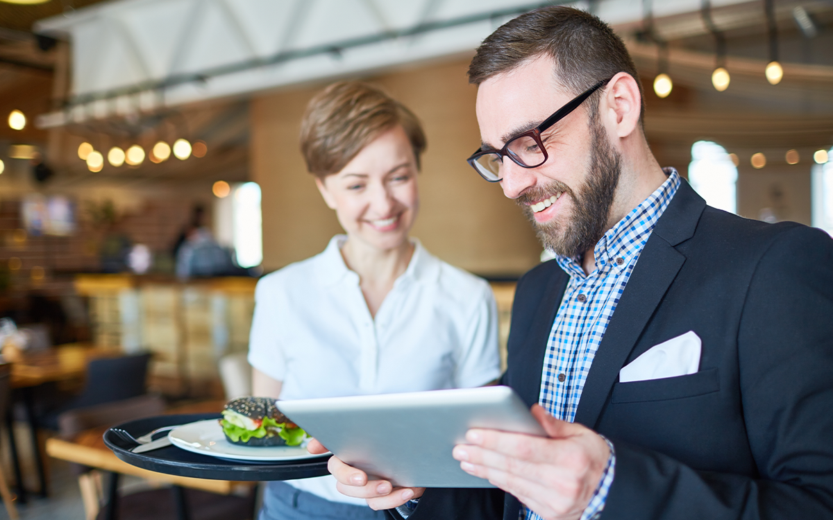 Ein Mann und eine Frau stehen in einem Betriebsrestaurant und unterhalten sich über die Digitalisierung